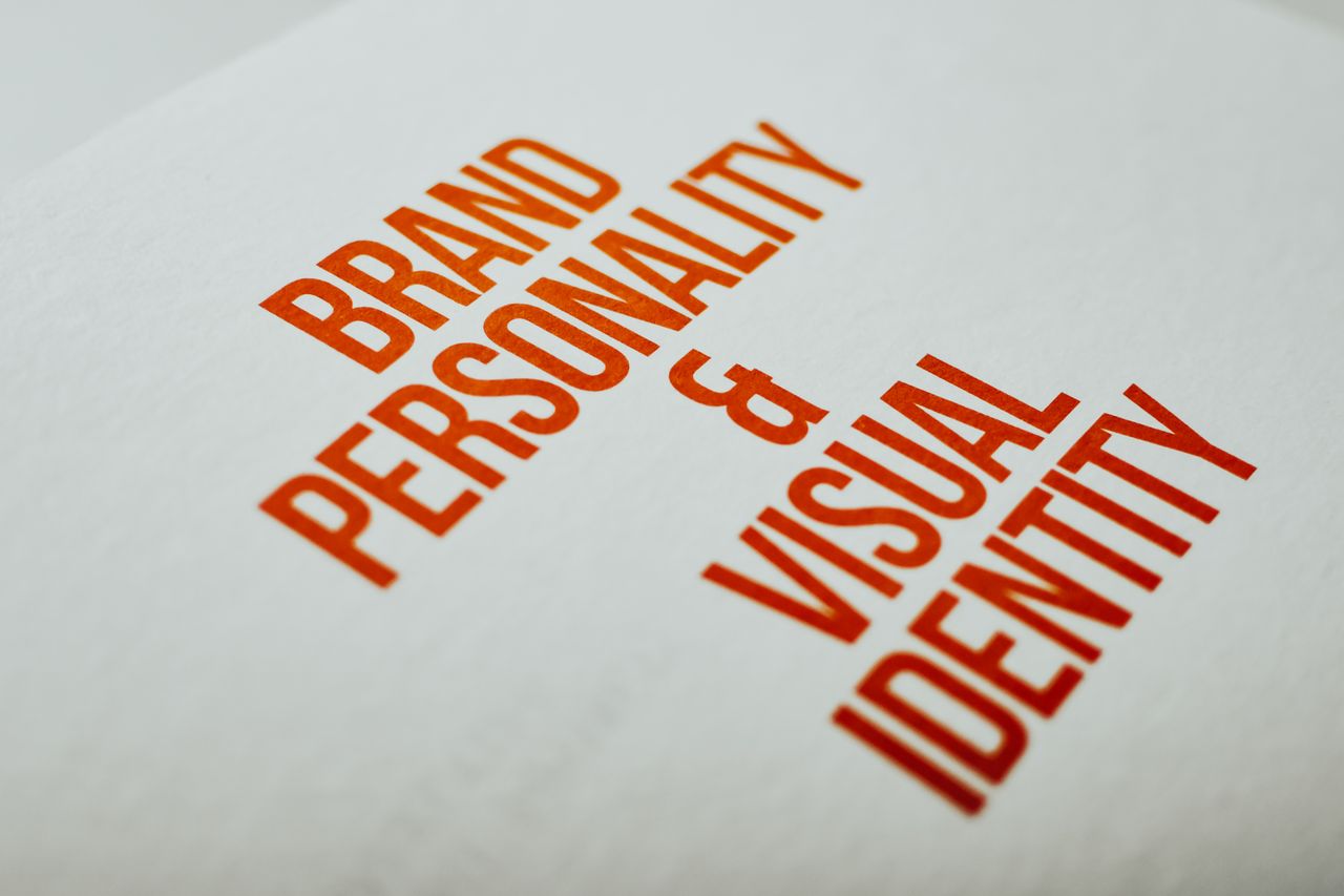 Vue rapprochée du texte Brand Personality & Visual Identity en rouge sur papier blanc.